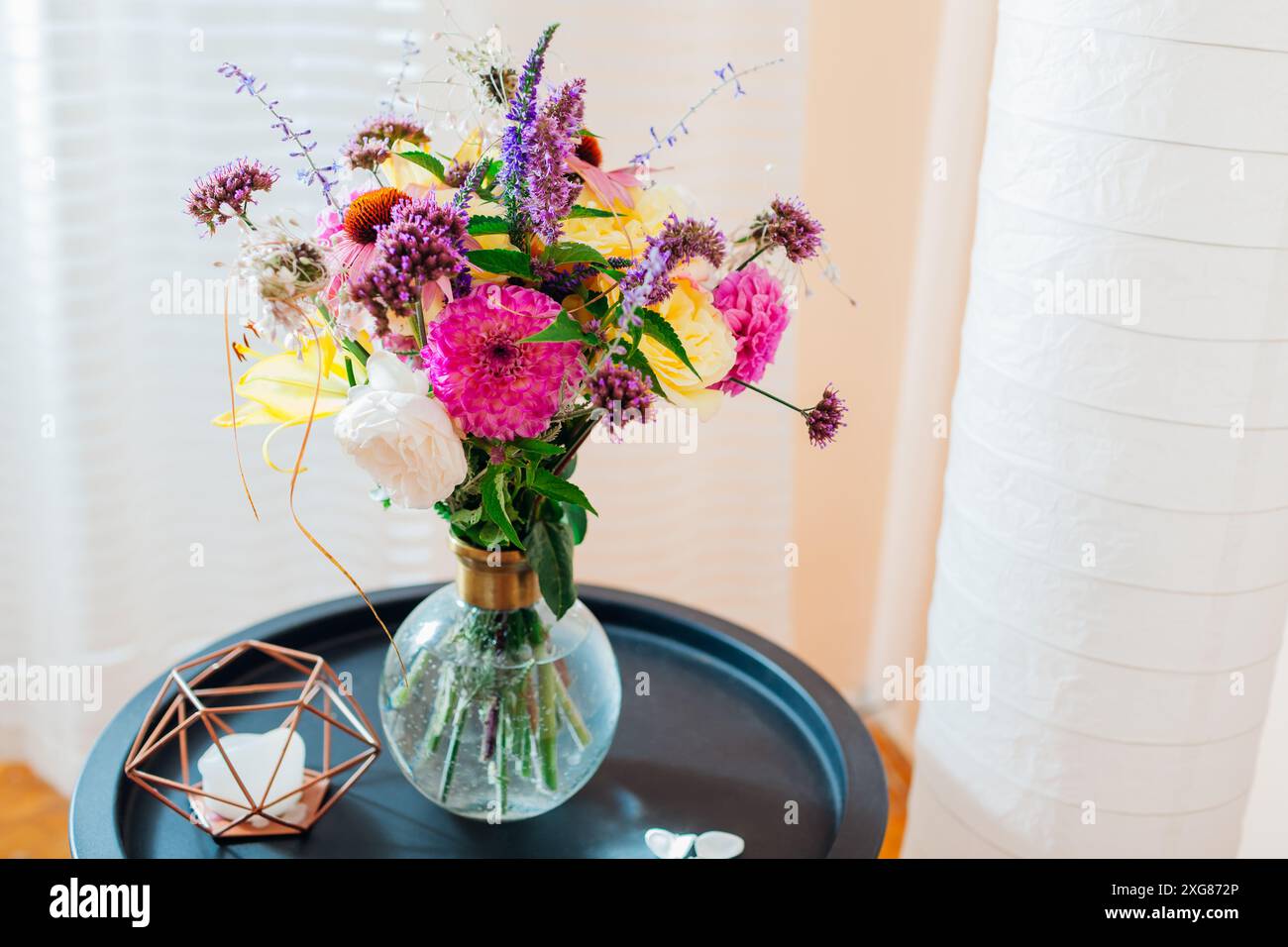 Blick von oben auf den frischen Sommerstrauß in transparenter Vase auf dem Tisch. Rosa, gelbe, lila Blüten. Blumenarrangements zu Hause aus Dahlien, Rosen, ver Stockfoto