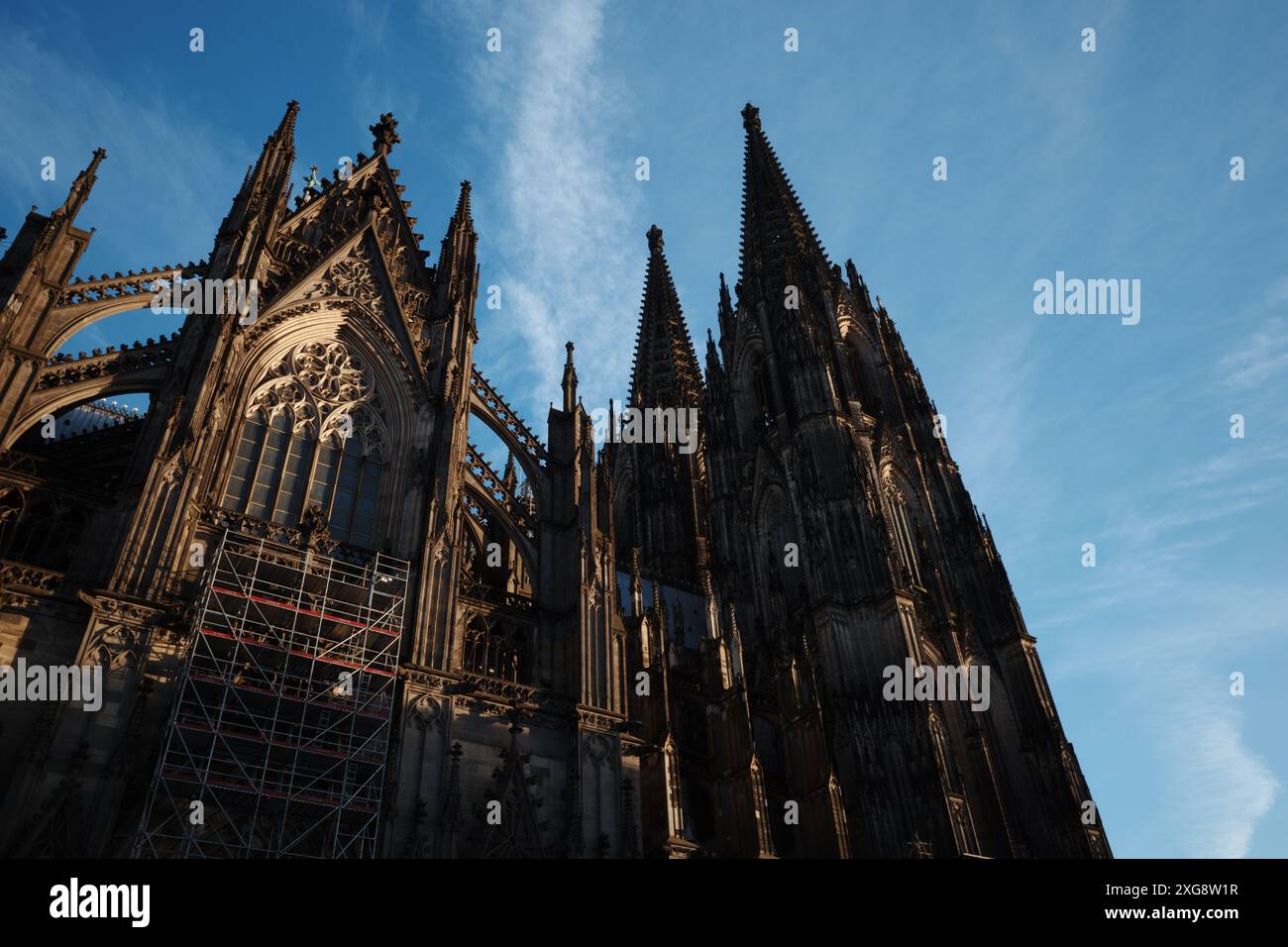 Ein atemberaubender Blick auf die gotische Fassade einer historischen Kathedrale mit komplexen architektonischen Details und hohen Türmen vor einem klaren blauen Himmel A Stockfoto