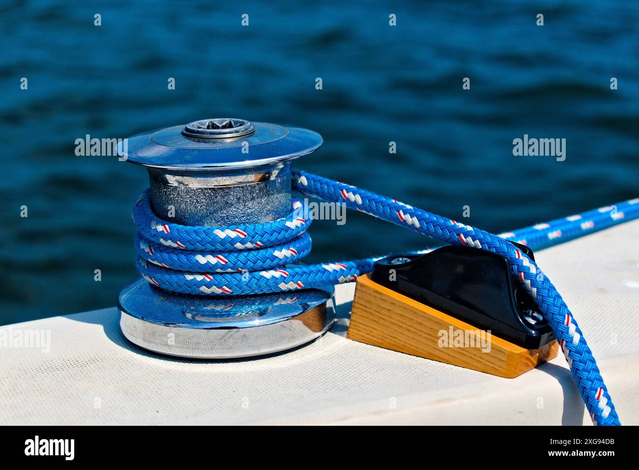 Eine Winde, die benutzt wird, um die Segel auf einem Segelboot zu verstellen, mit einem blauen Seil, das umwickelt ist, während es den Fluss hinauffährt. Stockfoto