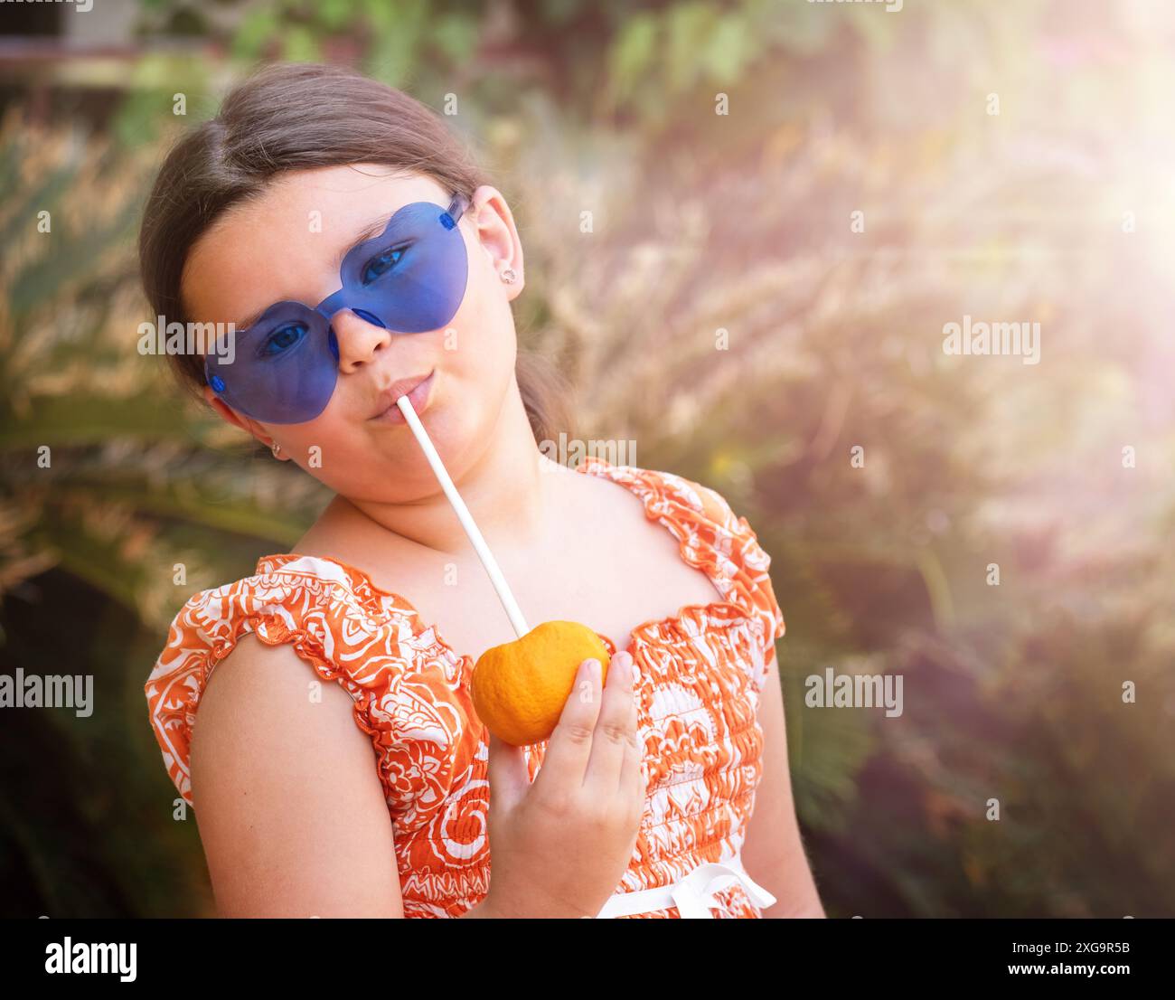 Kind trinkt Mandarinensaft in den Tropen im Urlaub Stockfoto