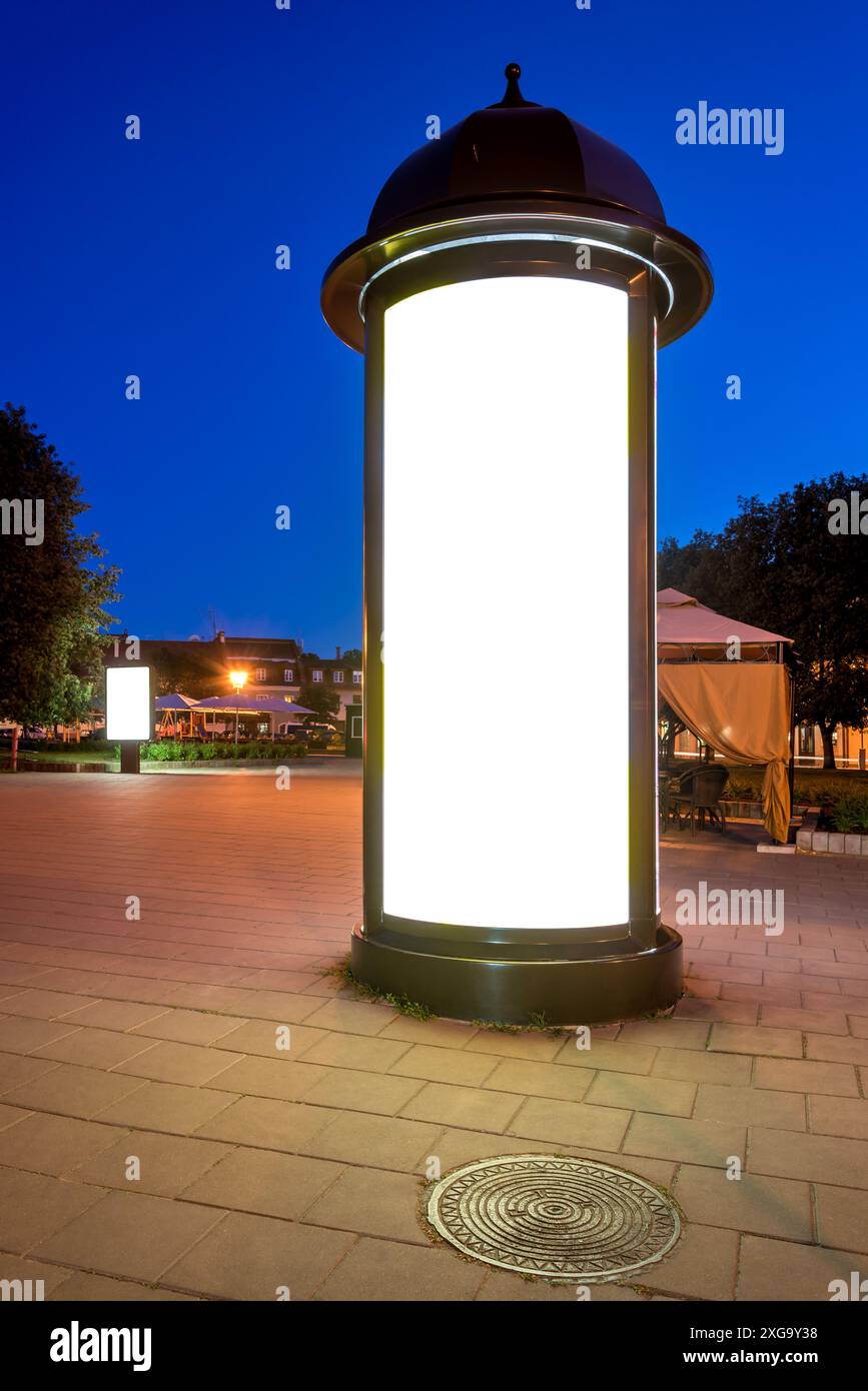 Leeres Modell einer runden Reklametafel auf Einem Stadtplatz bei Nacht. Klassischer Säulenlichtkasten In Der Altstadt Stockfoto