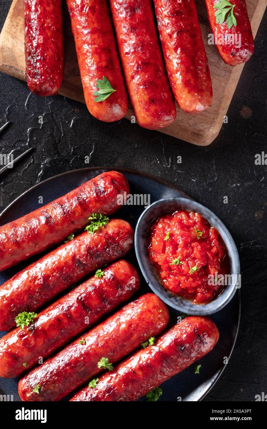 Würste, von oben auf dunklem Grund geschossen, mit Petersilie und Ketchup. Gourmet-bbq-Menü Stockfoto