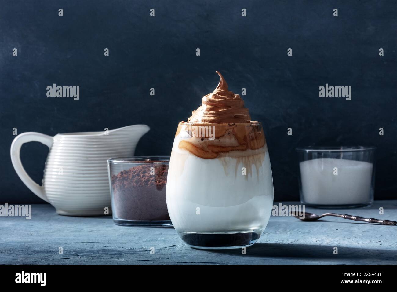 Dalgona kalter Kaffee mit Zutaten und Kopierraum, auf einem dunkelblauen Hintergrund. Süßes koreanisches Getränk Stockfoto