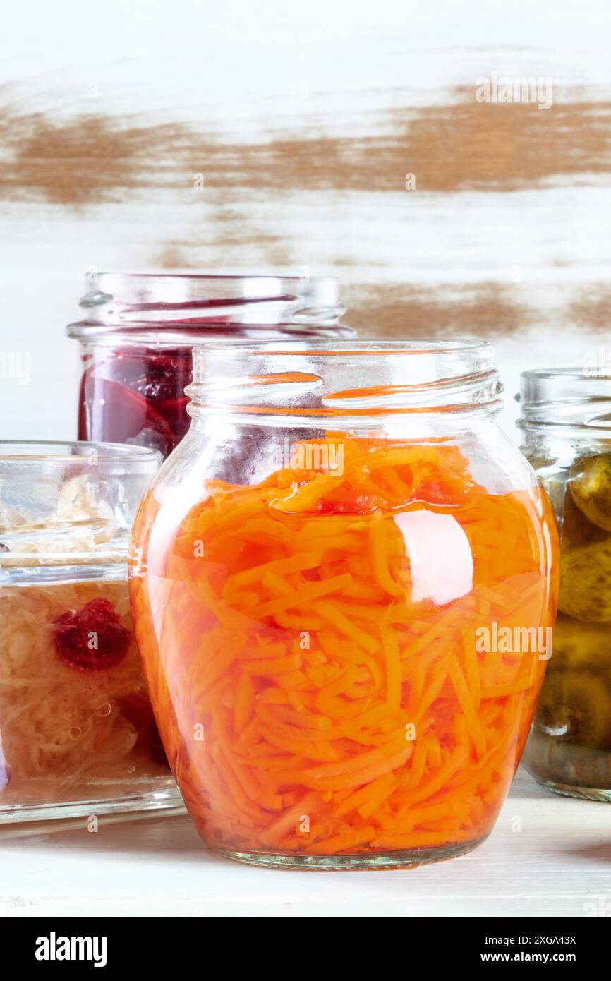 Ein Glas eingelegter Karotte mit anderen fermentierten Lebensmitteln im Hintergrund. Gemüse einkochen, hausgemachte Konfitüren Konzept mit einem Platz für Text Stockfoto