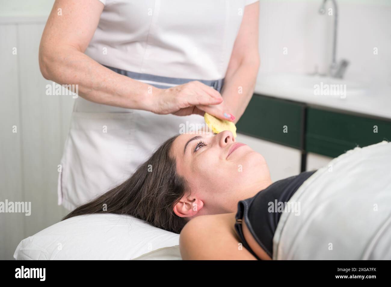 In einem Schönheitssalon führt eine Kosmetikerin Make-up-Entfernung vom Gesicht des Kunden durch. Hochwertige Fotos Stockfoto