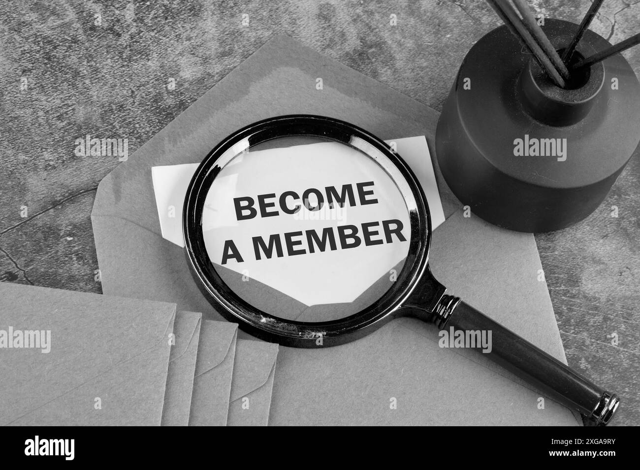 Die Inschrift BECOME A MEMBER erschien durch eine Lupe auf einem Blatt Papier, das aus einem Umschlag herausragte. Schwarzweißbild Stockfoto