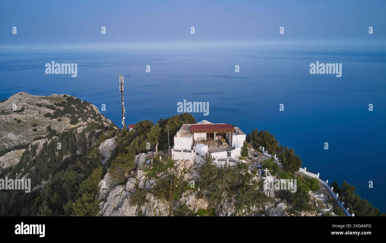 Drohnenaufnahme, Ein Gebäude mit einer Antenne auf einem Hügel umgeben von Bäumen und dem Meer, Panagia Kyra Kirche, über Tsambika Beach, Aussichtspunkt, Tsambika Stockfoto