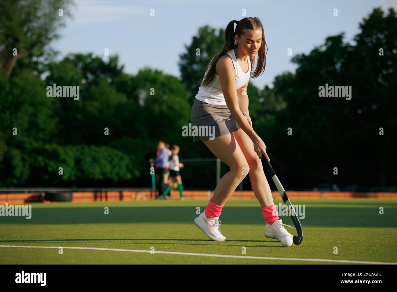 Hockeyspielerin spielt an einem sonnigen Tag Feldhockey, Hockeyspielerin schlägt den Ball mit einem Stock, Feldhockey-Konzept Stockfoto