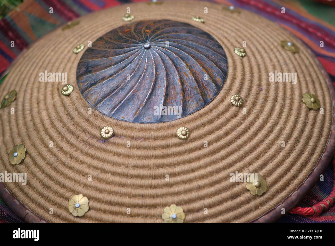 Eine detaillierte Ansicht eines dekorativen Schildes mit einem zentralen Metallkopf mit einem wirbelnden Muster, umgeben von einem gewickelten Seil und mit Messingblume verziert Stockfoto