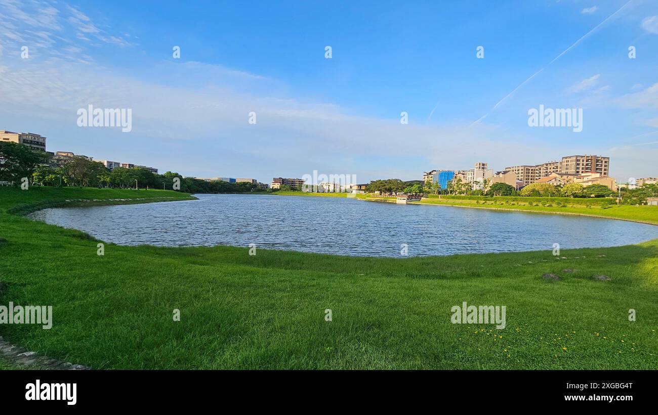 Ein ruhiger Stadtpark mit einem See, grünem Gras und Gebäuden im Bezirk Qingpu Zhongli, Taoyuan City, Taiwan Stockfoto