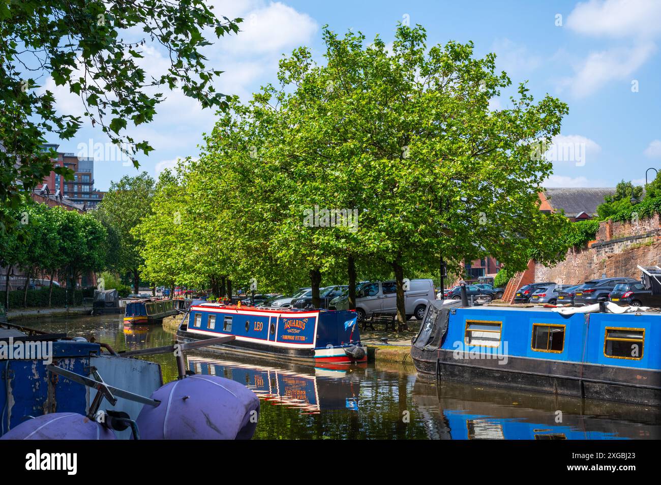 Schwarzkahn, Liftbrücke und Bäume im Castlefield Bridgewater Canal Basin, Manchester, Großbritannien, an einem sonnigen Juni-Tag mit blauem Himmel. Stockfoto