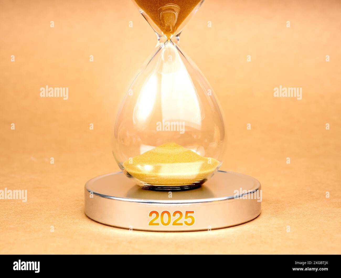 In Kürze für das neue Jahr 2025: Business and Technology Concept. Nahaufnahme Sanduhr mit goldenem Sand innen, auf rundem silberchromchromhaltigem Podium mit 2025 Jahren Stockfoto