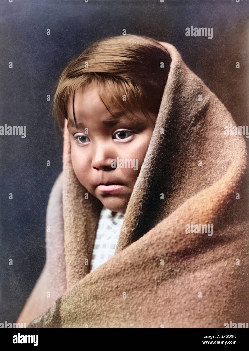 Navajo-Indianerkind mit einer Decke um Kopf und Schultern. Von Edward Curtis, um 1904, coloriert und restauriert. Stockfoto