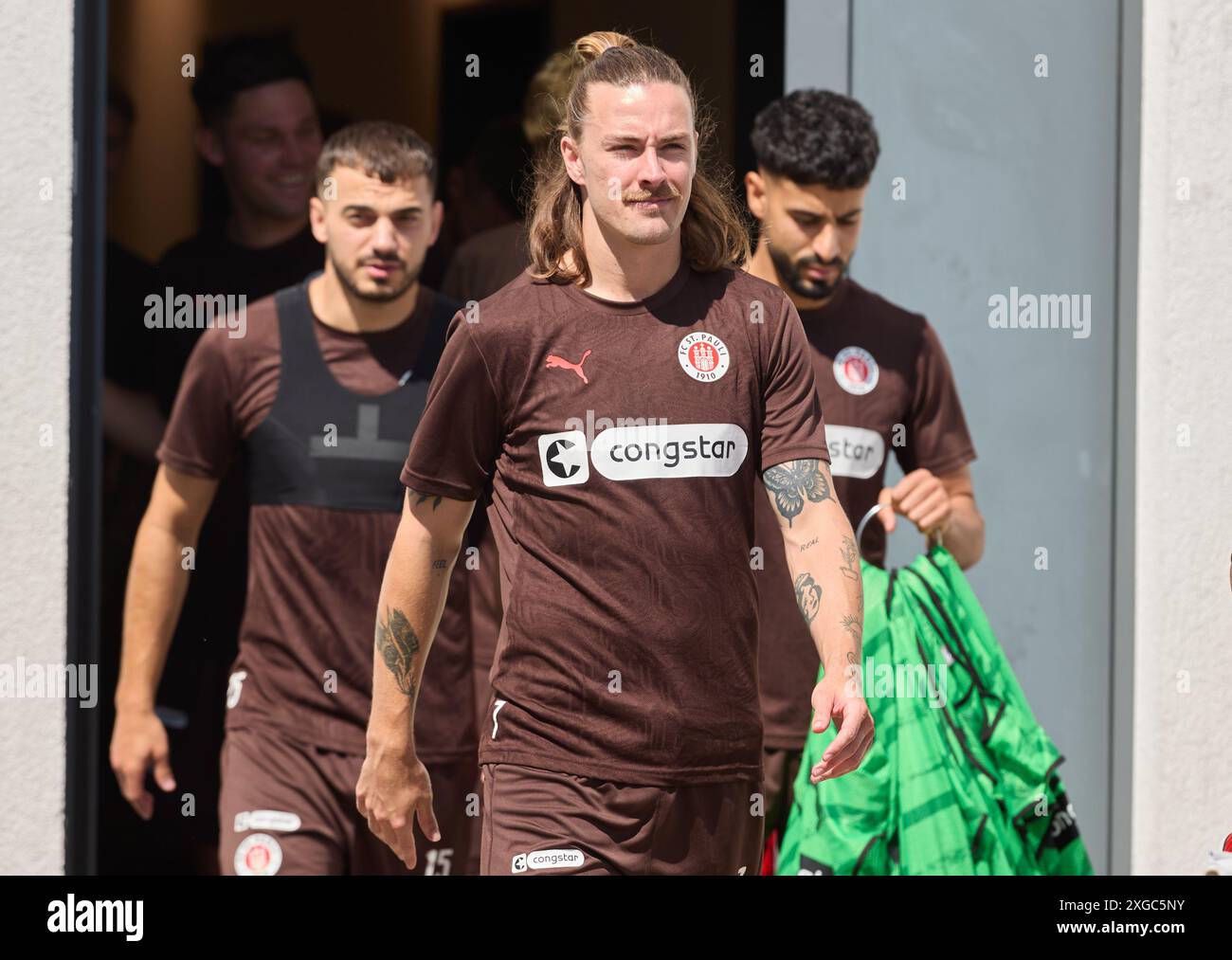 Hamburg, Deutschland. Juli 2024. Fußball: Bundesliga, Trainingsauftakt FC St. Pauli. Die Profi-Fußballspieler Danel Sinani (l-r), Jackson Irvine und Elias Saad verlassen die Garderobe. Quelle: Georg Wendt/dpa/Alamy Live News Stockfoto