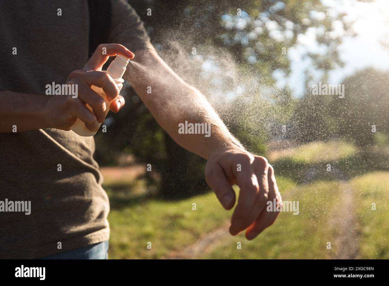 Mückenstich-Prophylaxe an sonnigen Sommertagen. Der Mann trägt Insektenschutzmittel auf seine Hand. Stockfoto