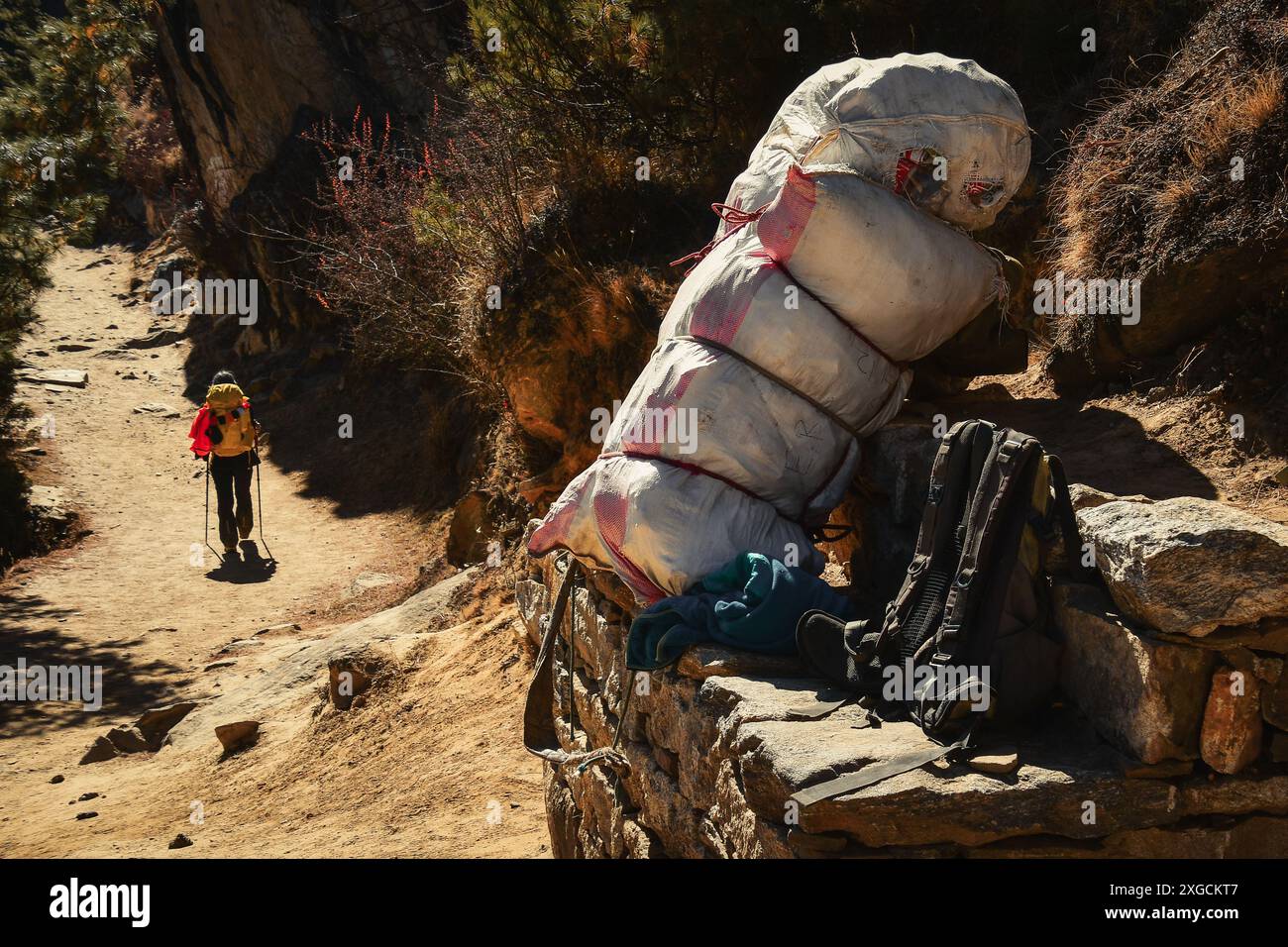 Sherpa-geladene Tragetasche gegen leichten Everest-Basislager-Trekker-Rucksack am Rande der EBC-Trek-Straße Stockfoto