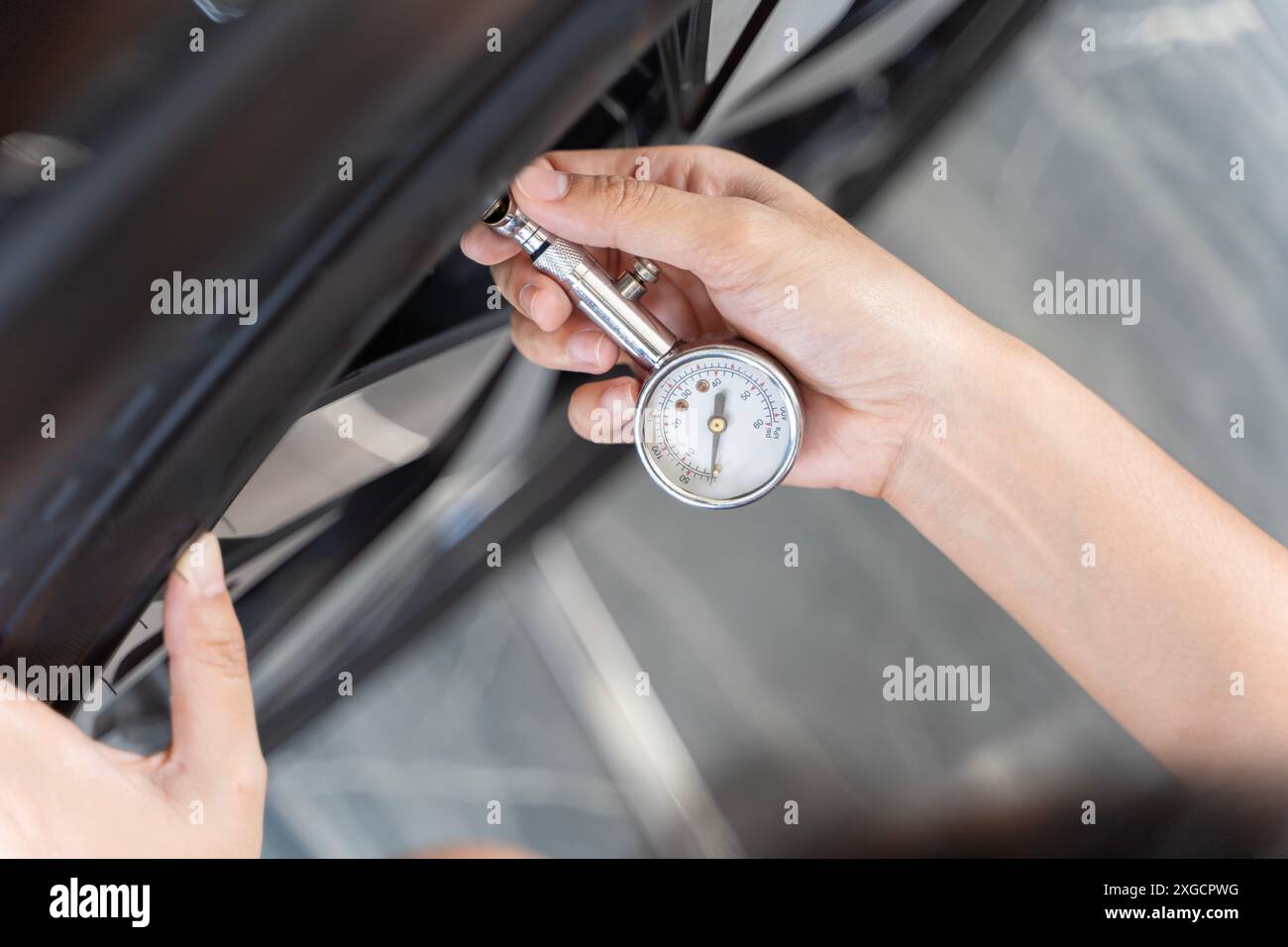 Nahaufnahme des Handdruckmanometers zur Reifendruckmessung. Mädchen überprüfen Sie die Reifen vor dem Verlassen. Mädchen überprüft den Zustand des Autos. Frau Überprüft Stockfoto