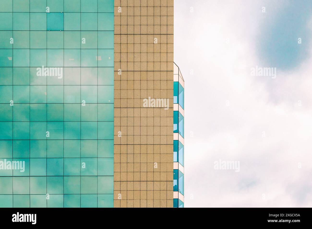 Abstrakte Ansicht eines modernen Gebäudes am Himmel. Mit Glasfenstern, die Wolken reflektieren, und klaren geometrischen Linien. Stockfoto