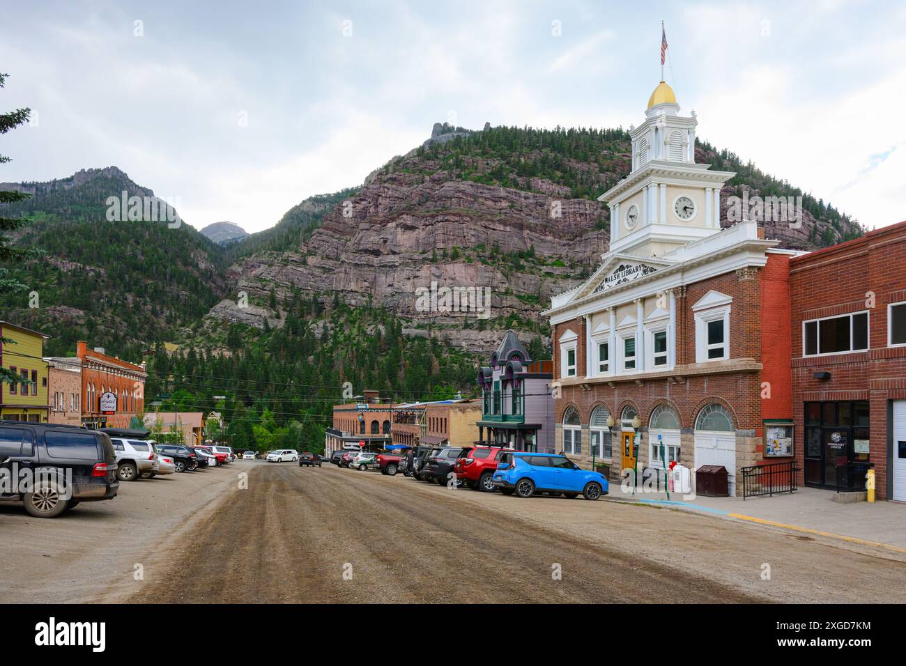 Ouray, CO, USA - 13. Juni 2024; Stadtbild von Ouray mit unbefestigter Straße, Walsh Library Gebäude und Berg Stockfoto