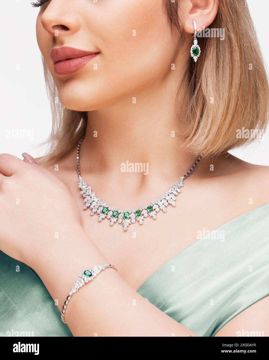 Elegante Frau mit luxuriösem Smaragd- und Diamantschmuck, einschließlich Halskette, Armband und Ohrringen. Stockfoto