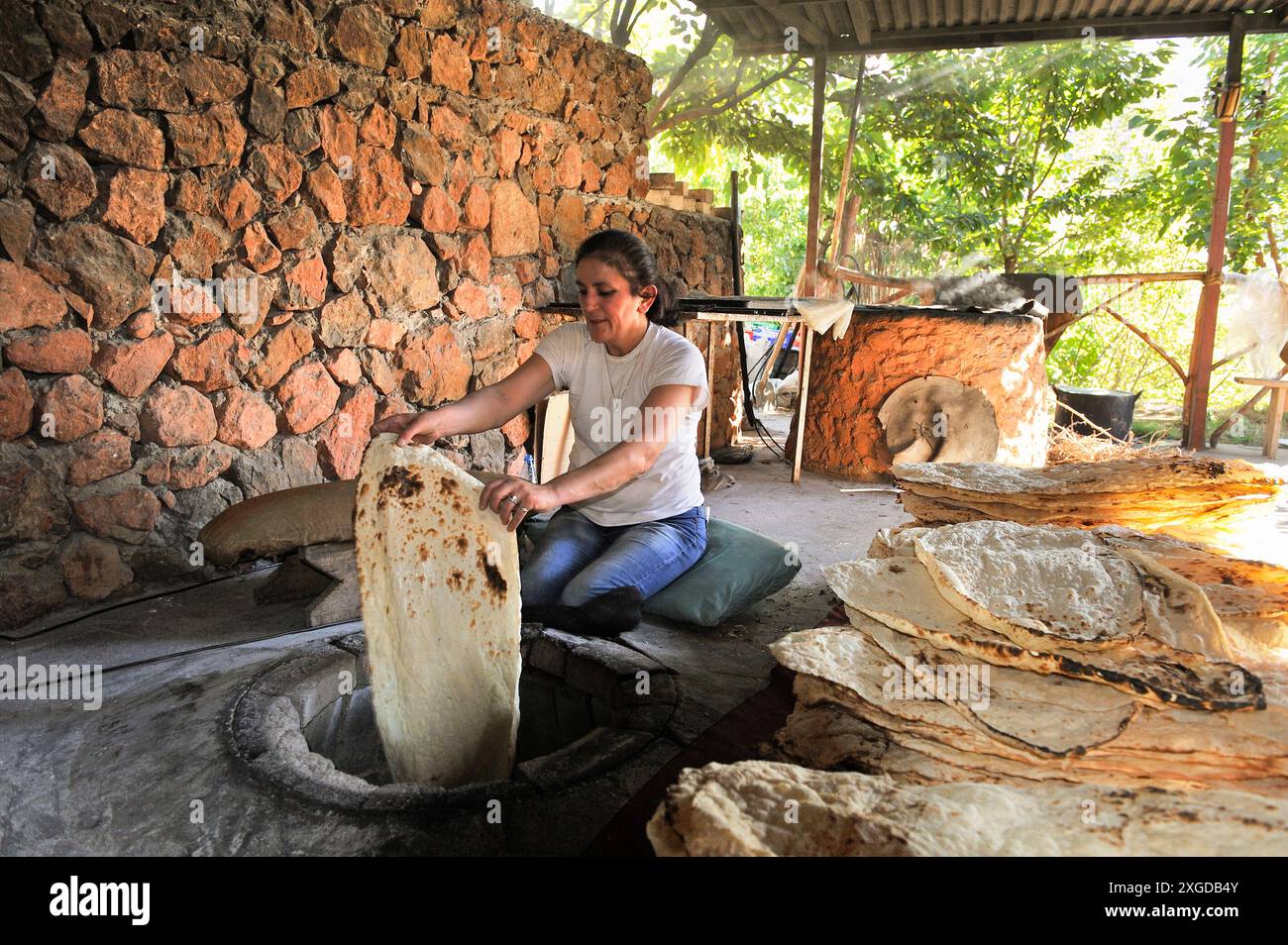 Frau, die Lavash (dünnes ungesäuertes Fladenbrot) in einem Tandoor, auf Armenisch Tonir genannt, in einem Restaurant neben dem Noravank-Kloster in der Nähe von Yeghe herstellt Stockfoto