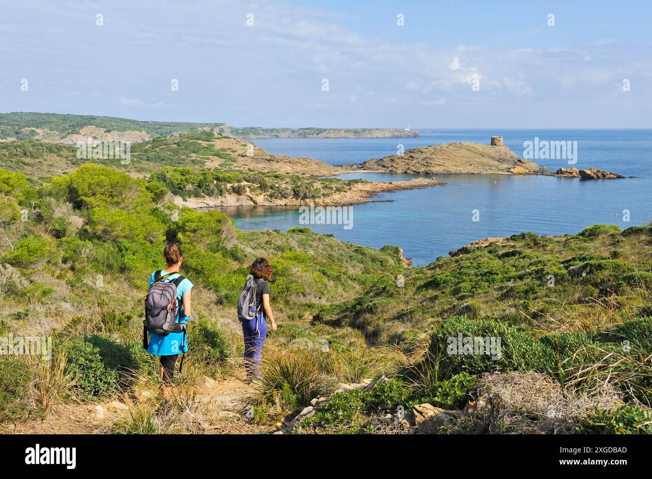 Wanderer auf dem Cami de Cavalls, Wanderweg GR 223, mit der Landzunge und dem Wachturm es Colomar im Hintergrund, s'Albufera des Grau Naturpark, M Stockfoto