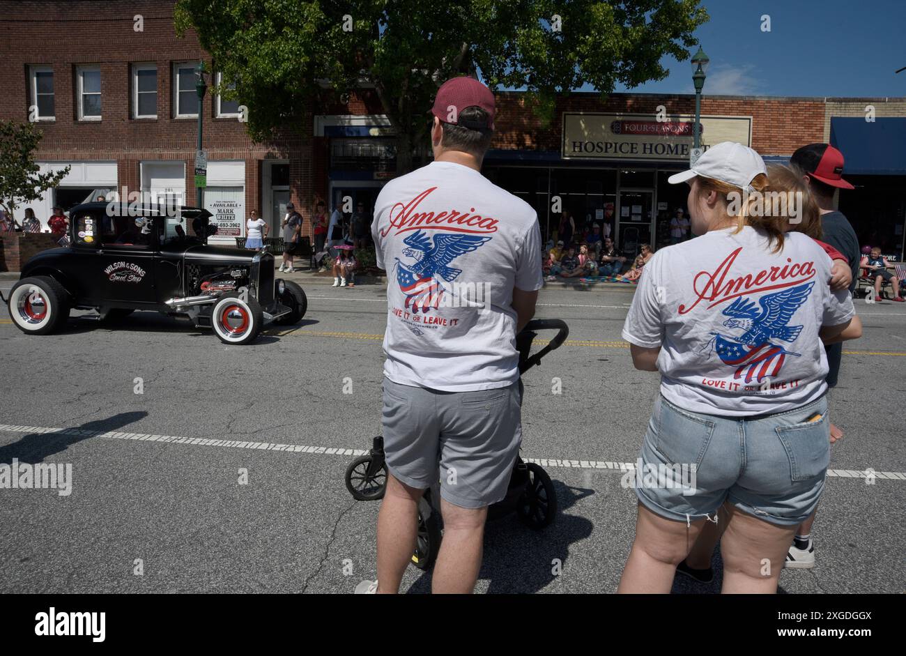 Ein Paar mit passenden „American Love IT or Leave IT“-T-Shirts sieht sich eine Parade am 4. Juli im Zentrum von Hendersonville, North Carolina, an. Stockfoto