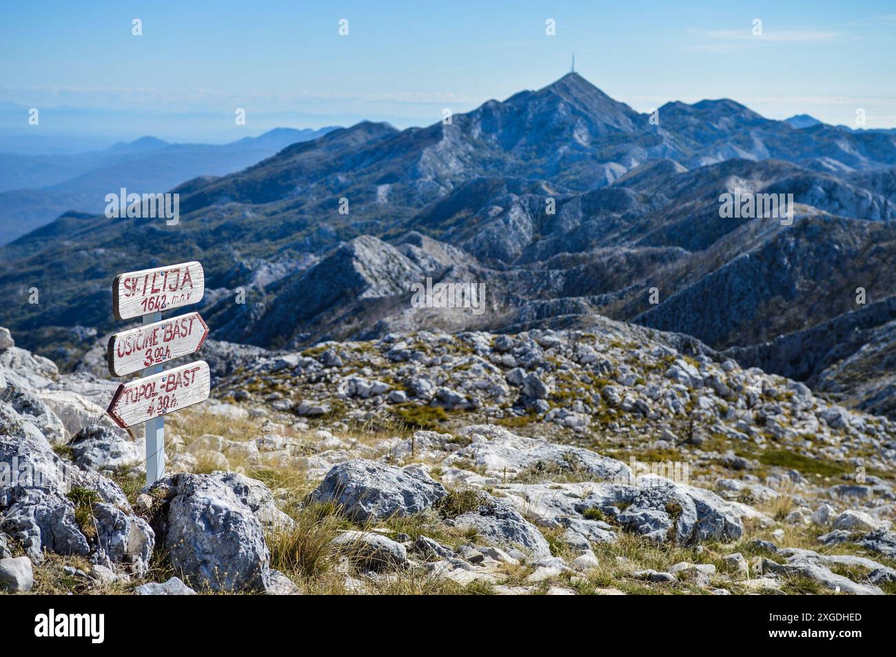 Wanderschild mit Entfernungen und Wegbeschreibungen am Gipfel von Sveti Ilija (St. Elias). Biokovo-Berg im Hintergrund Stockfoto