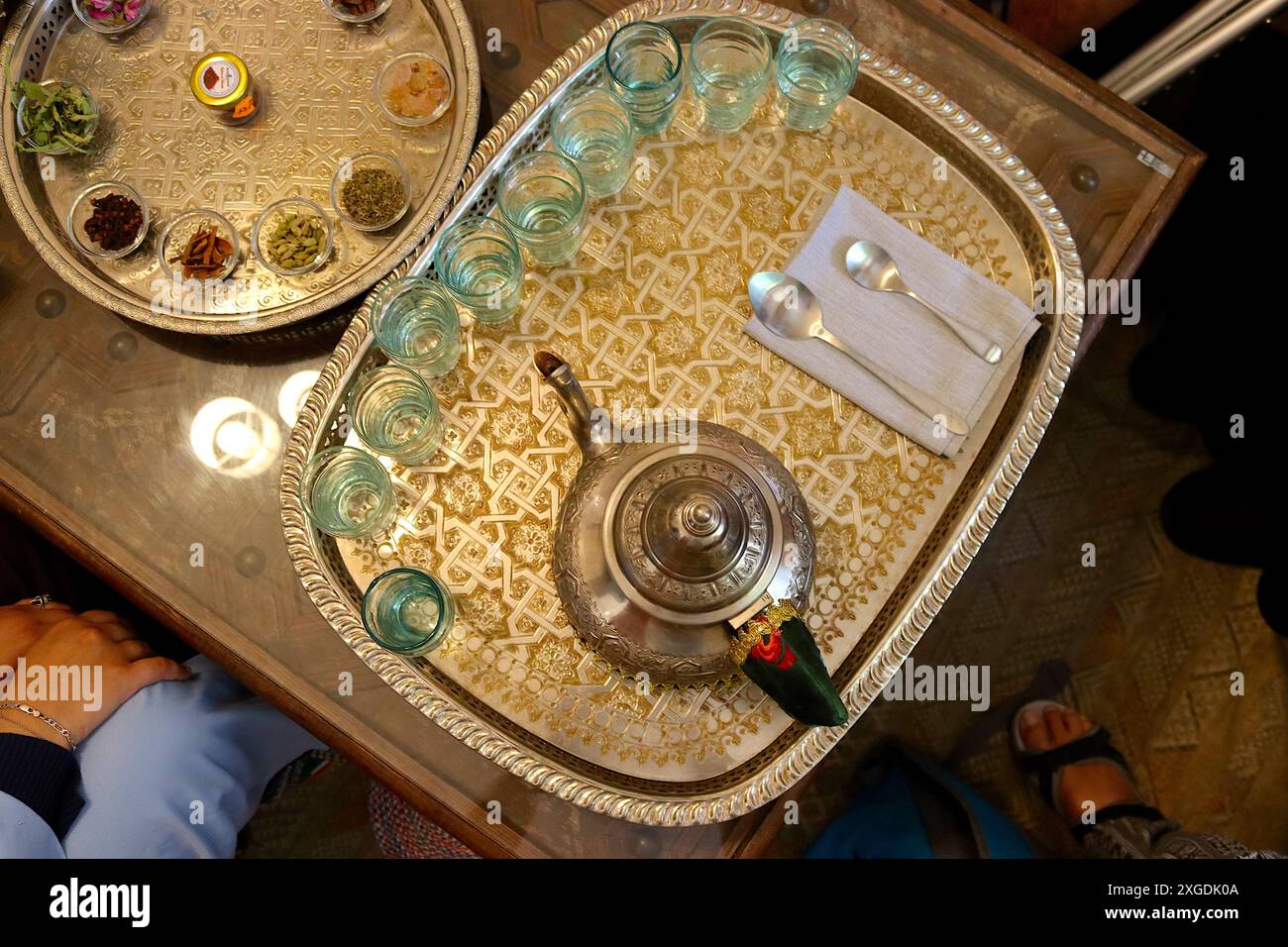 Blick auf ein traditionelles kulinarisches Erlebnis aus marokkanischem Pfefferminztee, präsentiert auf einem traditionell dekorierten silbernen Serviertablett mit Teekanne und Gläsern. Stockfoto