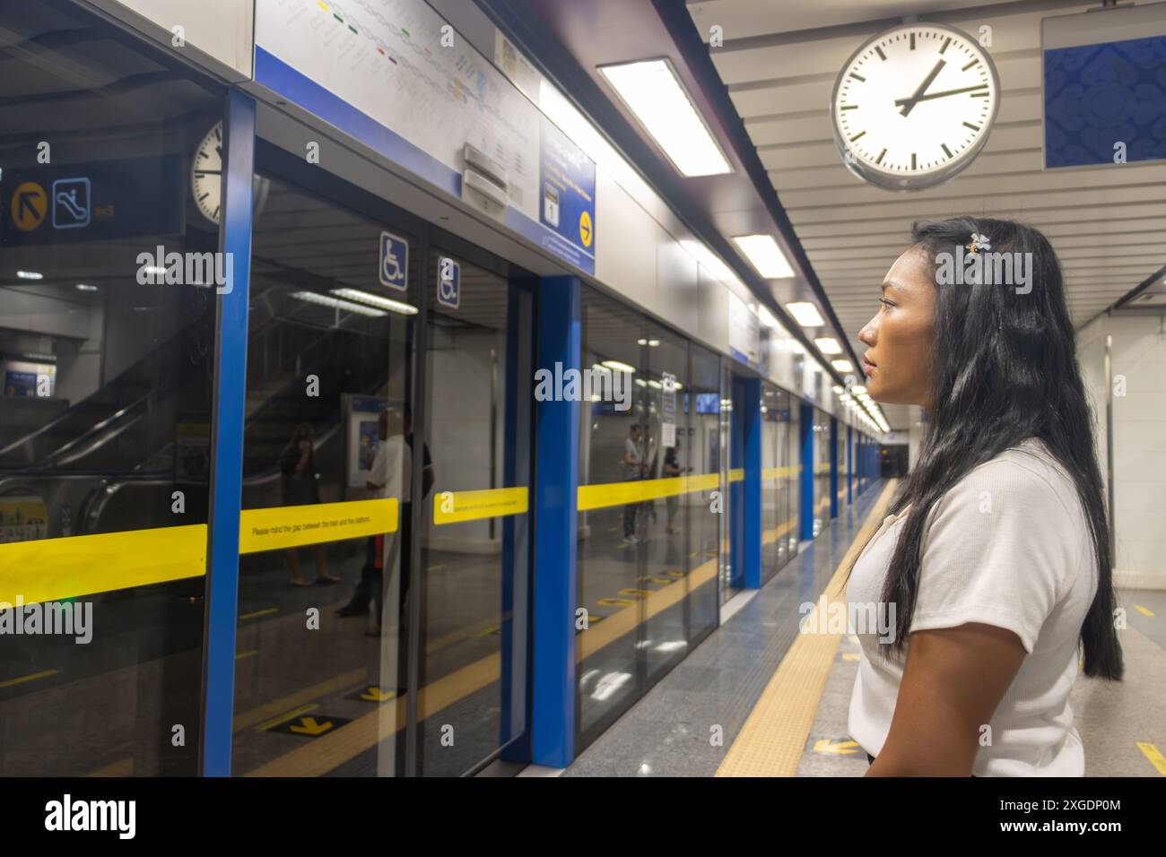 Eine junge Frau wartet auf einem unterirdischen Bahnsteig auf einen Zug Stockfoto