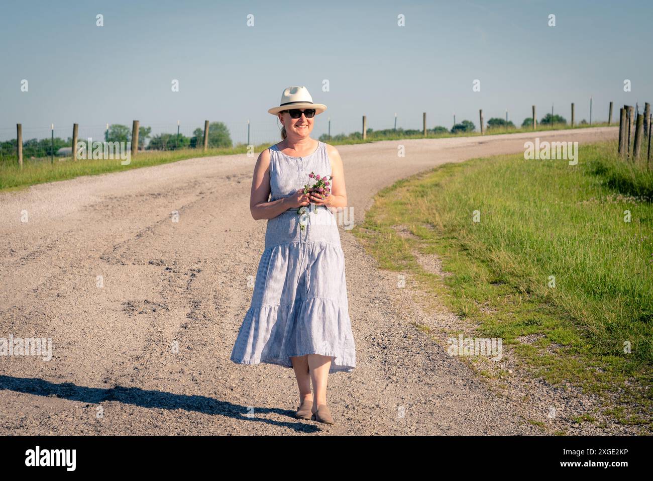 Glückliche reife Frau läuft an einem hellen Sommertag auf einer Landstraße. Stockfoto