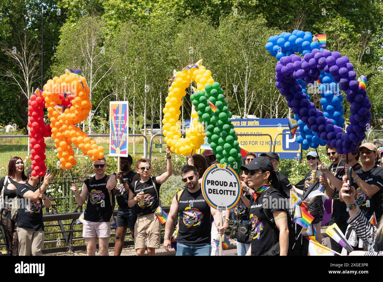 Mitarbeiter von Deloitte mit regenbogenfarbenen Ballonbuchstaben mit der Aufschrift „Proud“ und der Botschaft „Proud at Deloitte“ bei der Londoner Pride Parade am 29. Juni 2024 Stockfoto