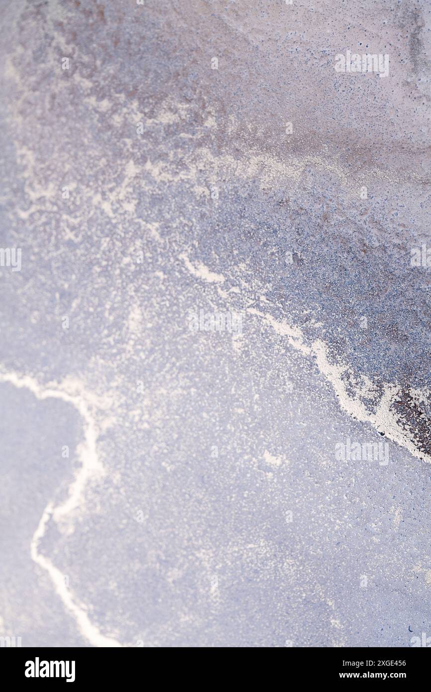 Nahaufnahme einer natürlichen, strukturierten Oberfläche mit einer silberweißen Linie, die sich durch einen Lavendelhintergrund schlängelt Stockfoto