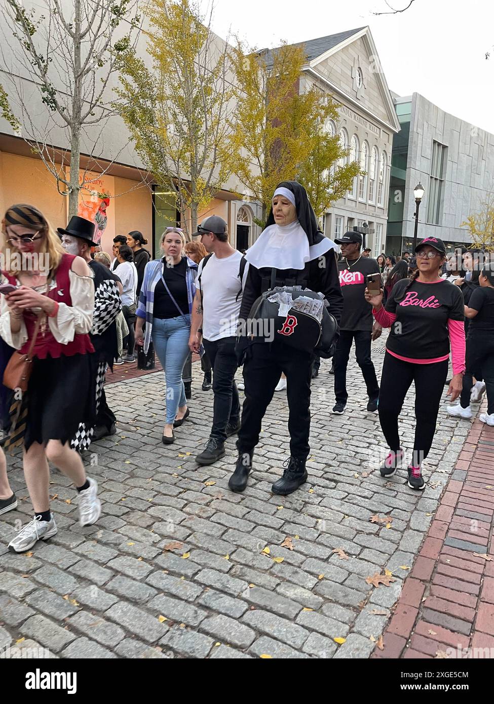 Menschen in lustigen Kostümen, darunter ein großer Mann im Nonnenkleid, ziehen während eines Halloween-Festivals durch die Innenstadt von Salem Massachusetts Stockfoto