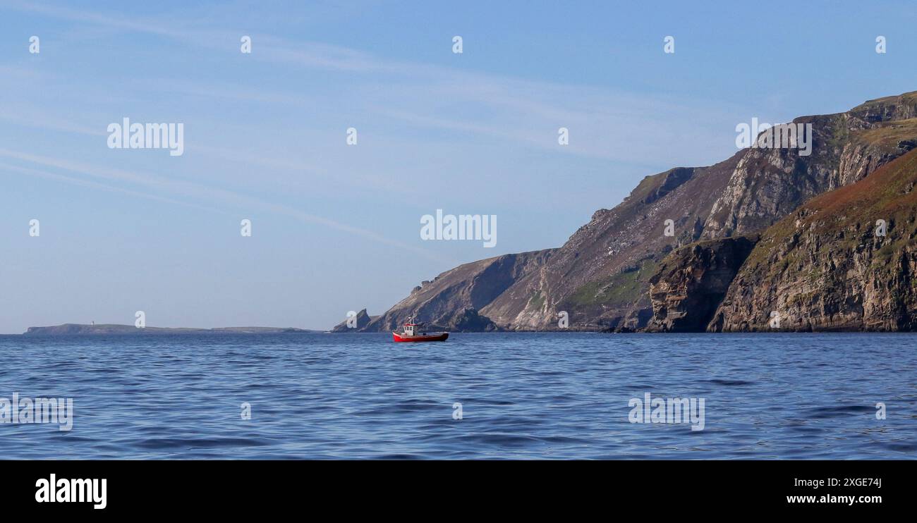 Rotes weißes irisches Fischerboot vor der Küste am Fuße der Klippen Slieve League County Donegal Irland. Stockfoto