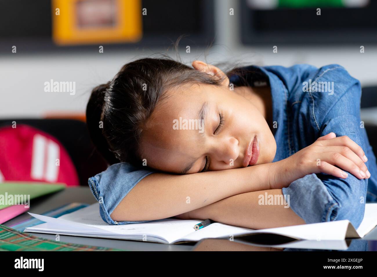 Müde birassische Schulmädchen, die am Schreibtisch sitzt, im Unterricht schläft, Kopierraum Stockfoto