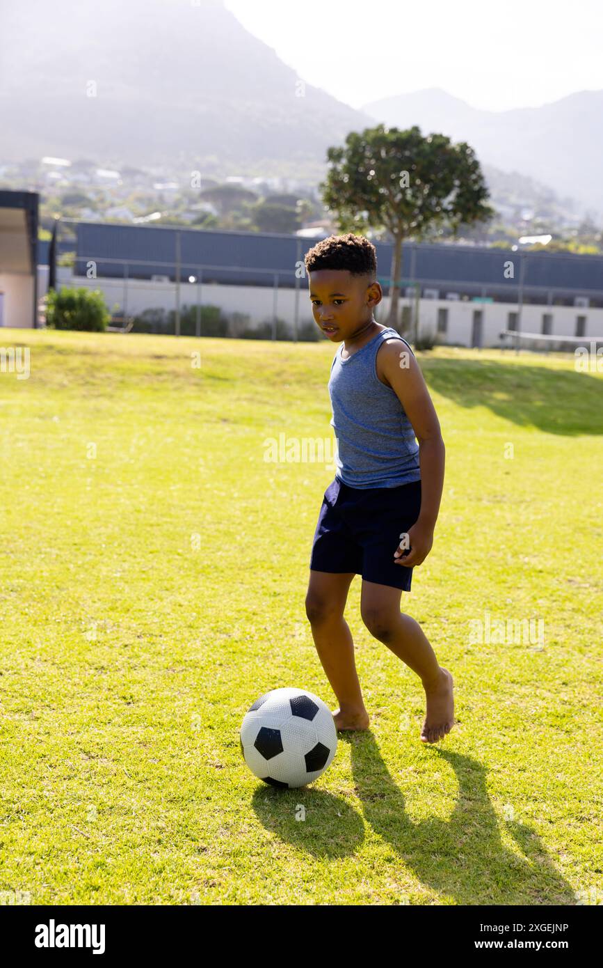 Glücklicher afroamerikanischer Schuljunge, der in der Schule Fußball spielt Stockfoto