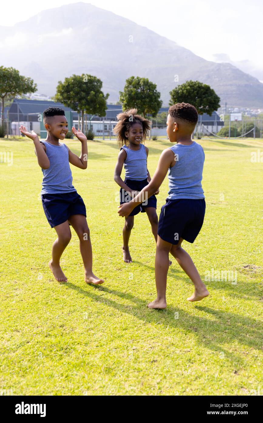 Glückliche afroamerikanische Schulkinder spielen Fußball auf dem Schulfeld Stockfoto