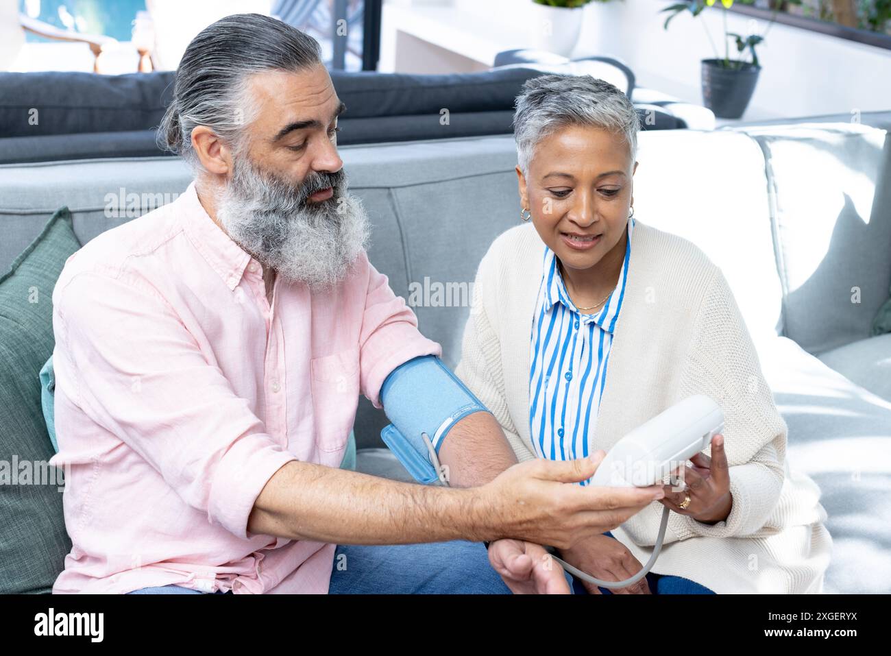 Blutdruck überprüfen, Seniorenpaar auf der Couch sitzen, sich auf Gesundheit konzentrieren Stockfoto