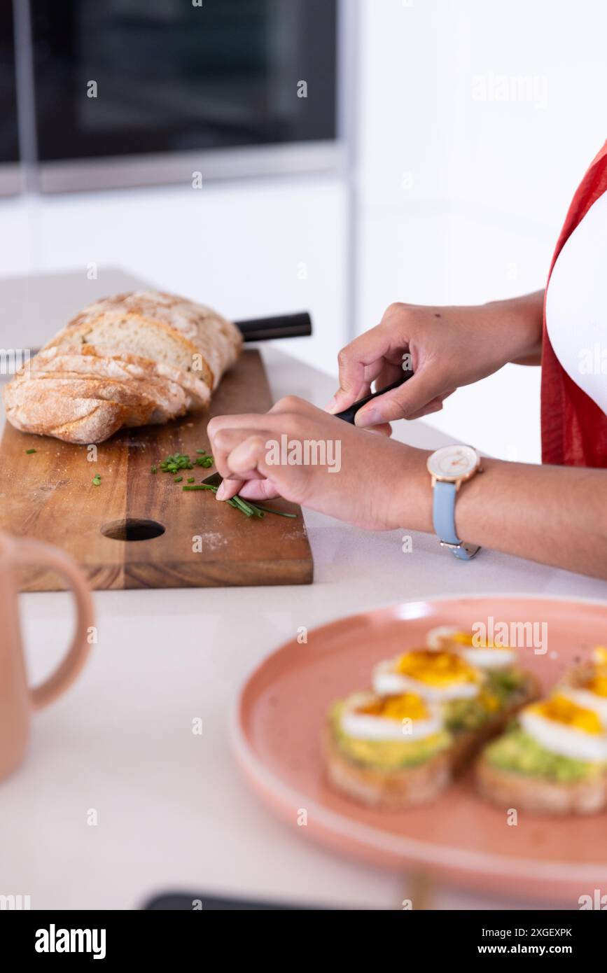 Gemüse auf Schneidebrett hacken, Frau, die das Frühstück mit Toast und Eiern zubereitet Stockfoto