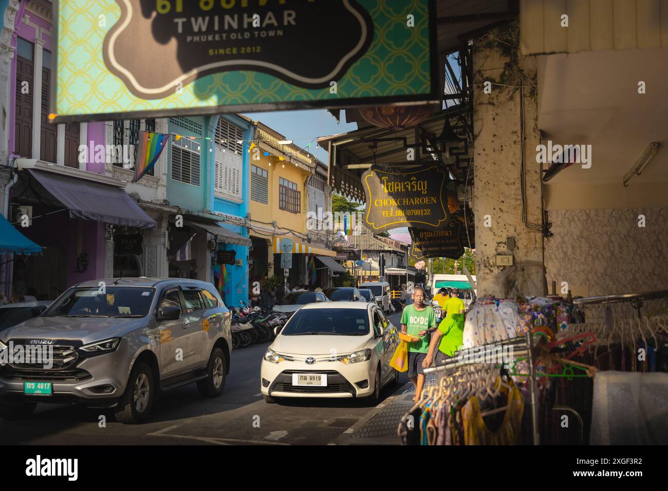 Thailand. Altstadt von Phuket mit farbenfrohen chinesisch-portugiesischen Gebäuden in der Altstadt von Phuket mit Motorrädern, Autos und Menschen auf der Straße. Geschäfte und Restaurants Stockfoto