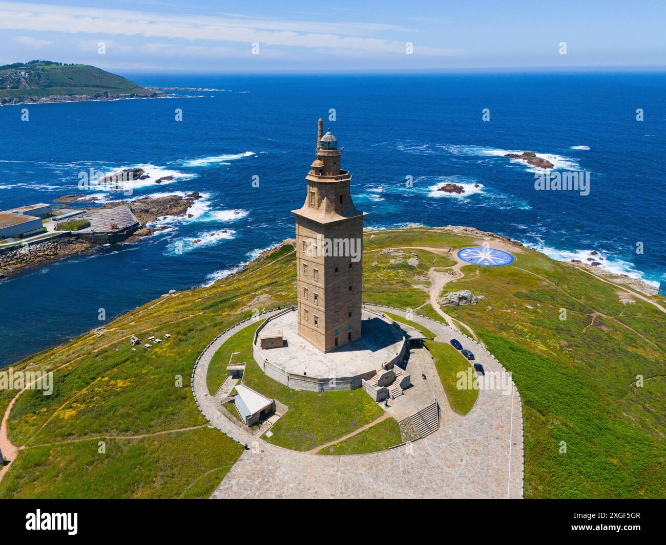 Antiker Leuchtturm auf einer Landmasse umgeben von kristallklarem blauem Ozean und grüner Vegetation unter klarem Himmel, aus der Luft, Torre de Hercules, Torre de Stockfoto