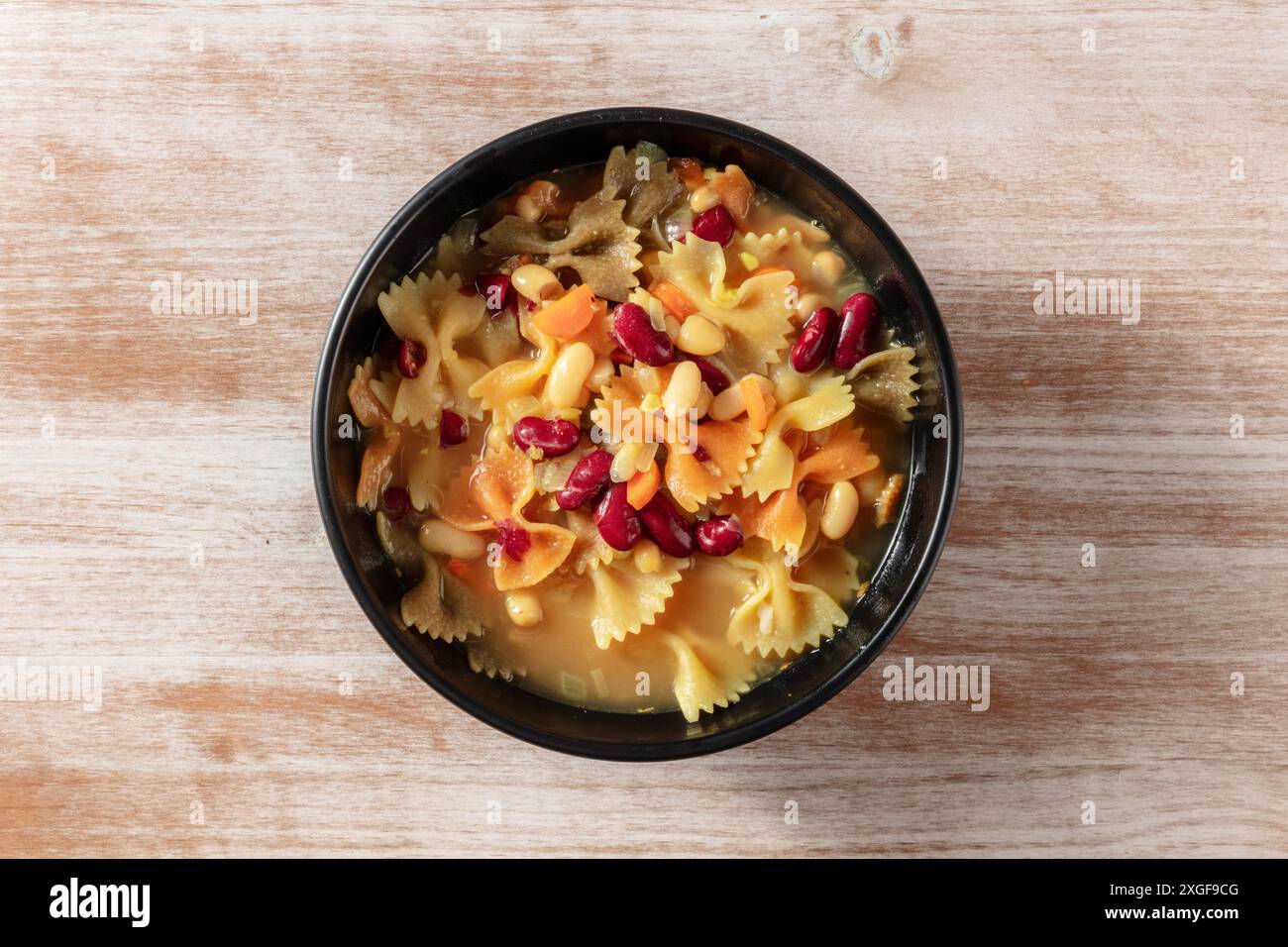 Vegane Suppe mit Pasta und Bohnen, Overhead-Schuss auf rustikalem Holzhintergrund Stockfoto