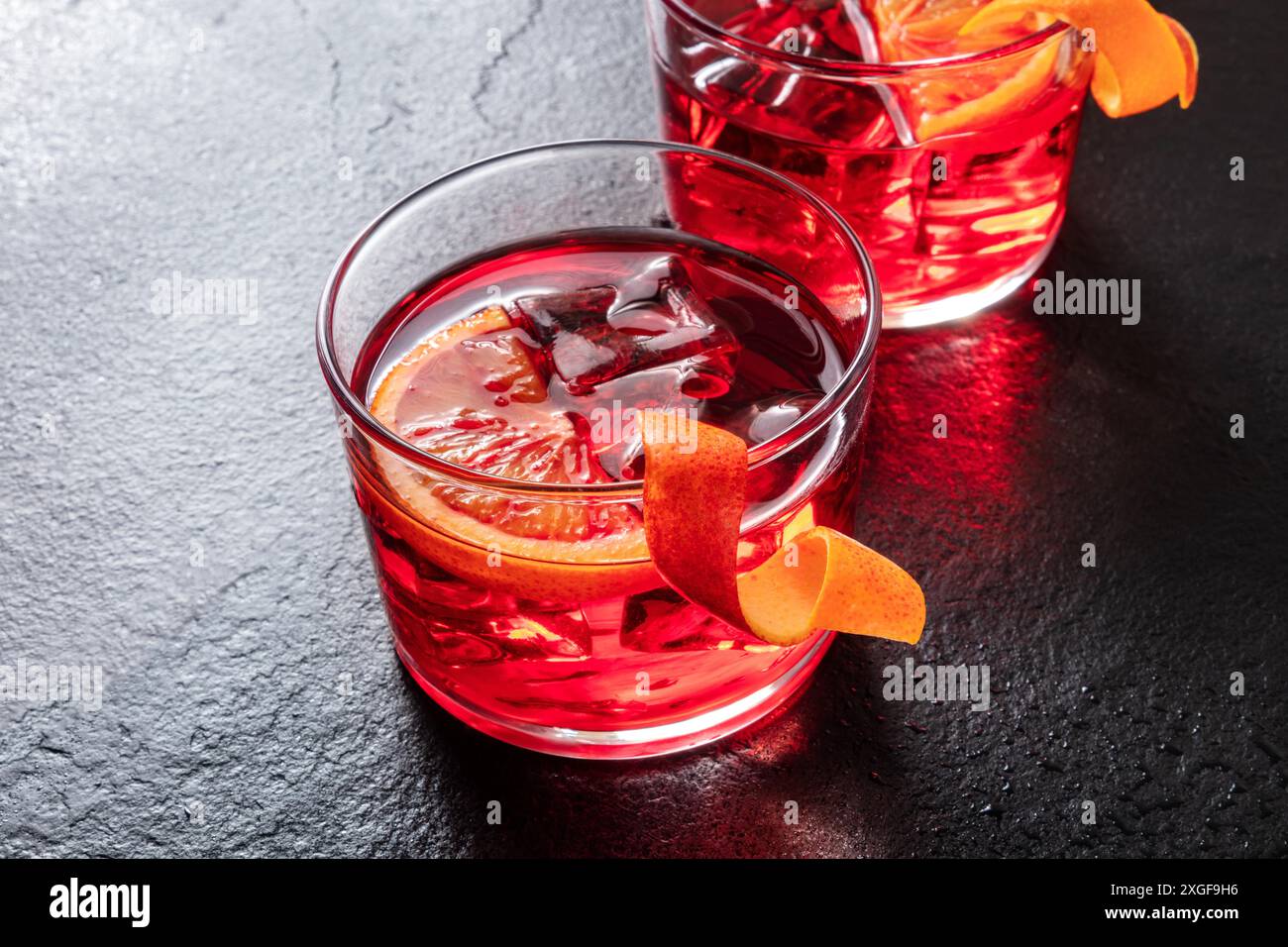 Negroni Cocktail mit Orangenschale und Eis auf einem schwarzen Hintergrund Stockfoto