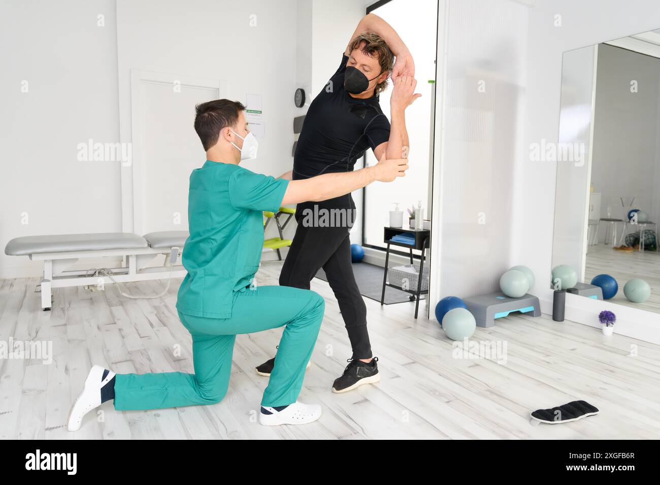 Physiotherapeut mit schützender Gesichtsmaske, die während der Coronavirus- oder Covid-19-Pandemie mit einem Patienten arbeitet. Hochwertige Fotos Stockfoto