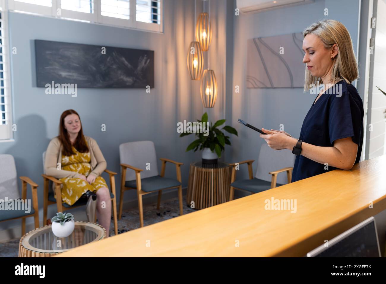 Rezeptionist mit Smartphone, während die Frau im Empfangsbereich der prothetischen Klinik wartet Stockfoto