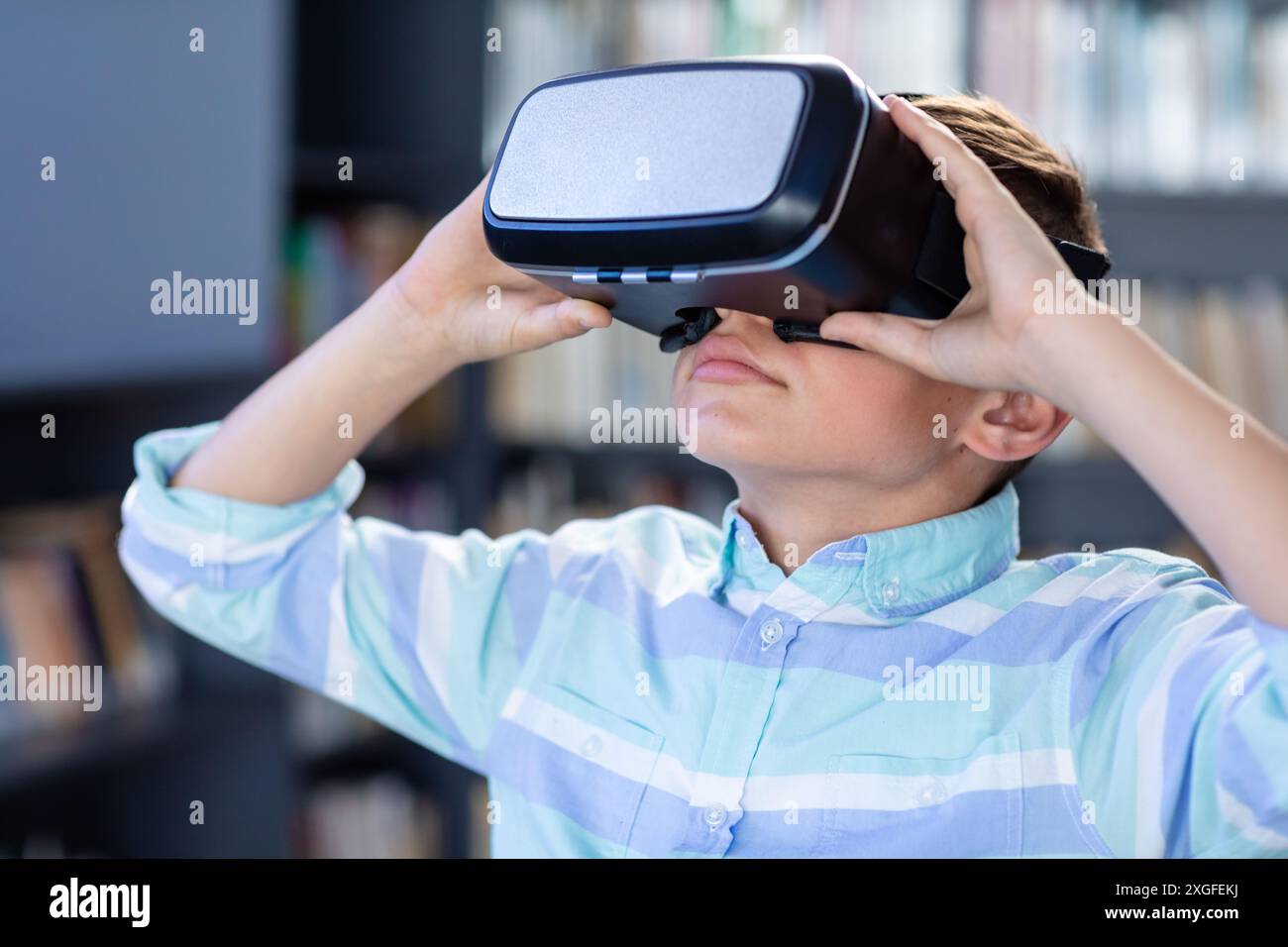 Kaukasischer Schuljunge mit vr-Headset in der Schulbibliothek, mit Kopierraum Stockfoto