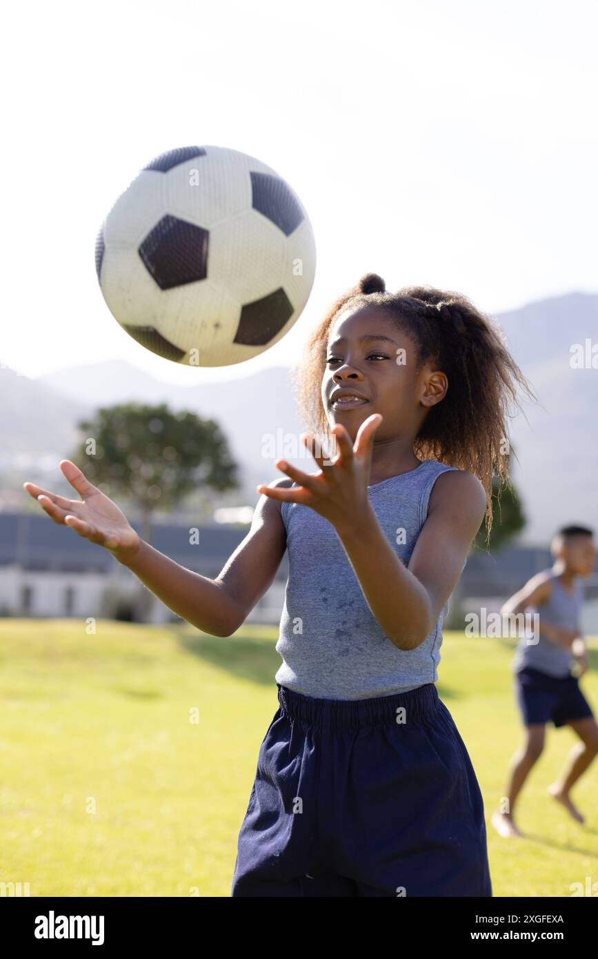 Glückliches afroamerikanisches Schulmädchen, das in der Schule Fußball spielt Stockfoto
