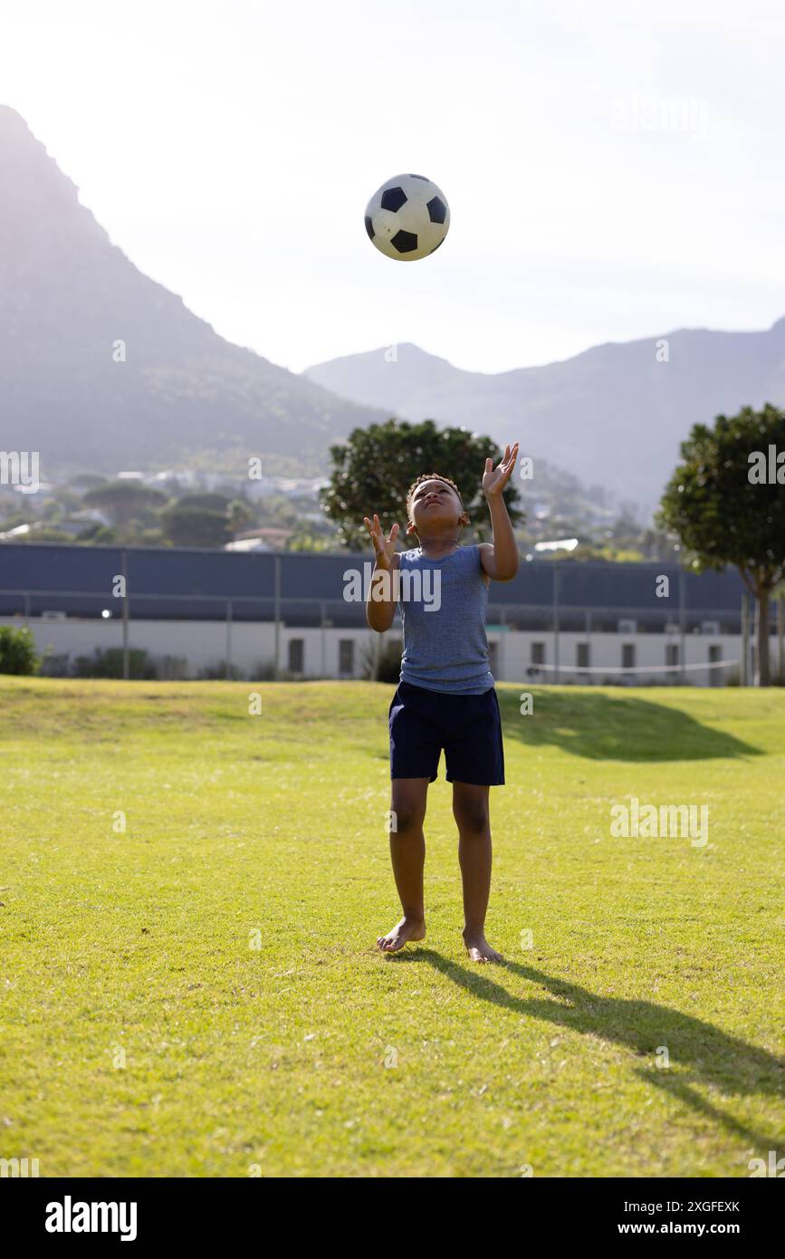 Glücklicher afroamerikanischer Schuljunge, der in der Schule Fußball spielt Stockfoto