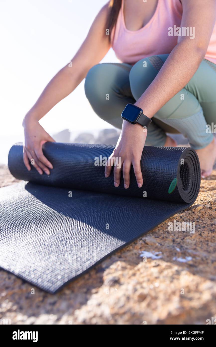 Die Yogamatte wird ausgerollt, die Frau bereitet sich auf das Training im Freien vor Stockfoto